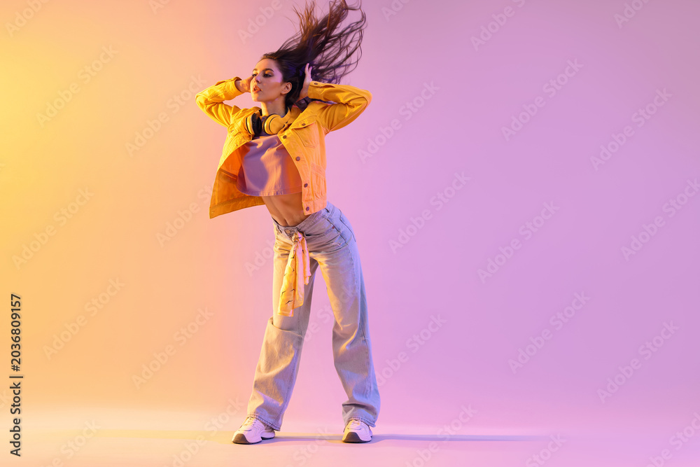 Obraz premium Young woman performing hip-hop dance on color background, space for text