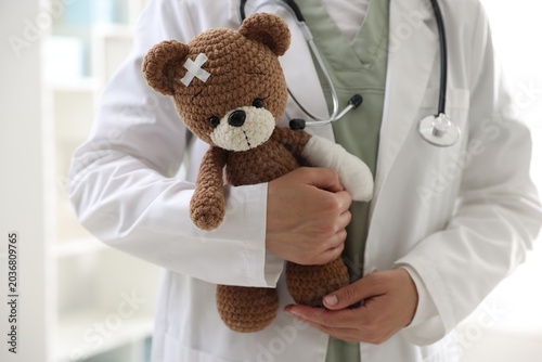Bild auf Leinwand Pediatrician holding teddy bear with adhesive bandages in clinic, closeup