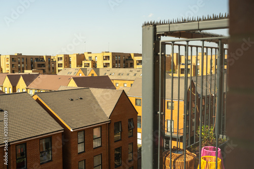 Urban residential buildings with balcony railing and cityscape under clear sky during daytime