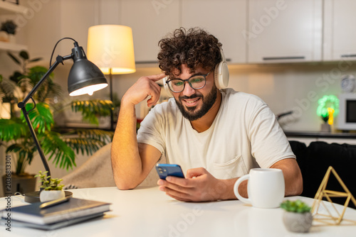 Tableau sur toile Arabian man at home wears wireless headphones listens music nods slowly enjoys calm, dancing