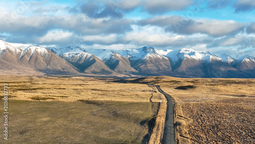 The road through a barren and arid  stunning  landscape to the mountains around Lake Oahu with snow on the peaks reflected on the village side of the Lake. One of my favourite lakes in NZ and the scen