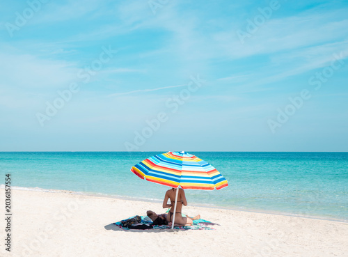 bikini woman on beach towel with colorful umbrella in miami florida