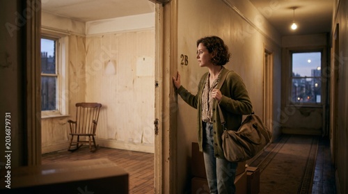 Young Woman with Bag Leaving Apartment and Taking One Last Look Before Moving Out