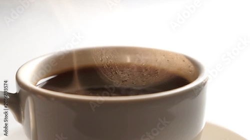 Close-up of hot black coffee with steam rising from the surface in a ceramic mug