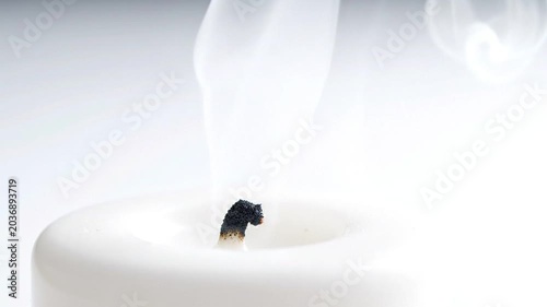 Wisps of white smoke gracefully ascend from a freshly extinguished candle wick, symbolizing a quiet conclusion and moments of serene reflection in a tranquil setting