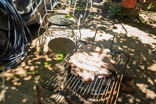 Parrilla con asado argentino de carne vacuna cocinándose sobre brasas durante reunión familiar de fin de semana
