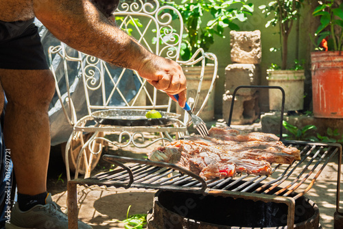 Parrilla con asado argentino de carne vacuna cocinándose sobre brasas durante reunión familiar de fin de semana