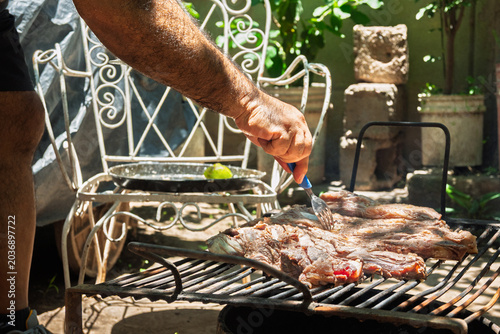 Parrilla con asado argentino de carne vacuna cocinándose sobre brasas durante reunión familiar de fin de semana