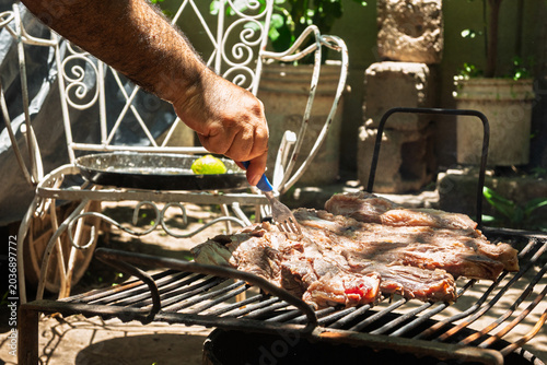 Parrilla con asado argentino de carne vacuna cocinándose sobre brasas durante reunión familiar de fin de semana