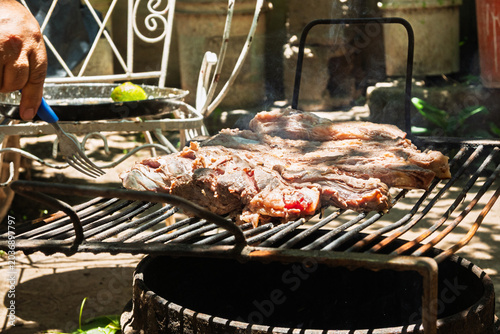 Parrilla con asado argentino de carne vacuna cocinándose sobre brasas durante reunión familiar de fin de semana