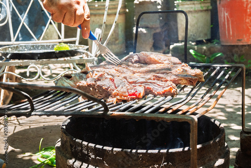 Parrilla con asado argentino de carne vacuna cocinándose sobre brasas durante reunión familiar de fin de semana