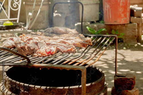 Parrilla con asado argentino de carne vacuna cocinándose sobre brasas durante reunión familiar de fin de semana