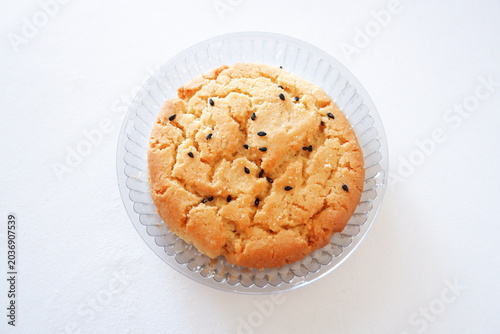Fényképezés Close-up of crunchy sesame biscuit on white background, golden baked cookie with black sesame topping and crumbly texture