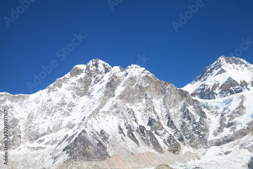 Everest base camp in off-season on the everest base trek, empty of tents and climbers, beneath himalayan peaks under a blue sky.
