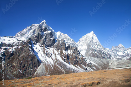 Majestic Himalayan mountains in Nepal with snow peaks and rocky terrain under a clear blue sky, showcasing the grandeur of nature in the Himalayas, ideal for adventure and travel enthusiasts.