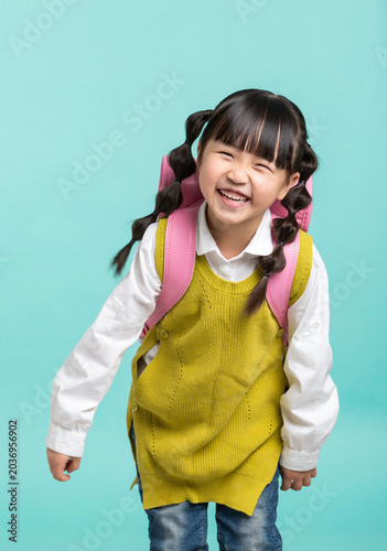 Obraz na płótnie A cheerful Asian female student, with her hair in gourd braids and carrying a pink backpack, stands against a blue-green background with a back-to-school theme