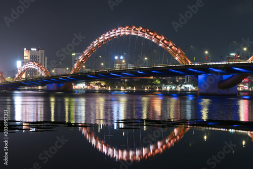 Bild auf Leinwand A long Dragon bridge with multiple glowing arches illuminated at night, casting