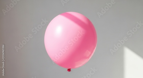 A single pink balloon floats against a neutral gray background with soft shadows.