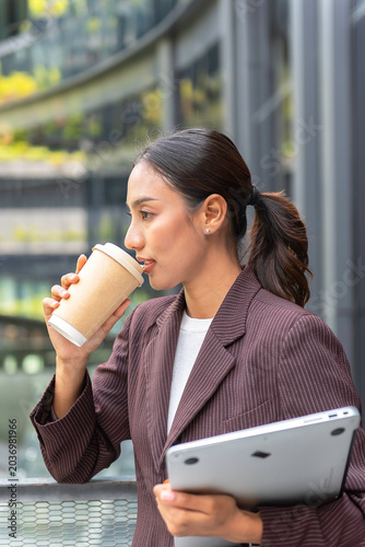 Close-up of female employee's hand holding a coffee cup and the other hand holding a laptop on the way to work.Business Concept
