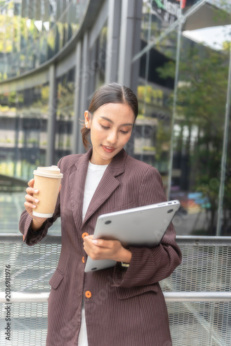 Close-up of female employee's hand holding a coffee cup and the other hand holding a laptop on the way to work.Business Concept