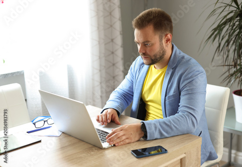 Tableau sur toile A man is concentrating on working on a laptop while sitting at a table