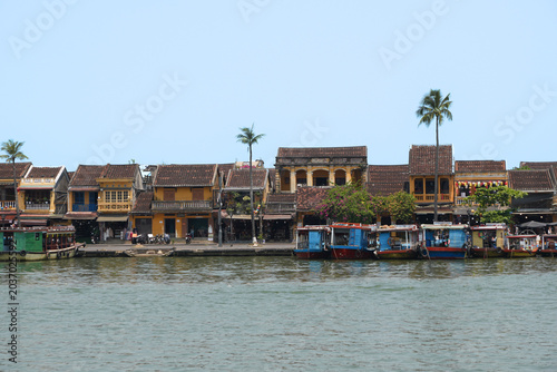 Fotografia Scenic view of traditional old yellow merchant houses and wooden tourist boats l