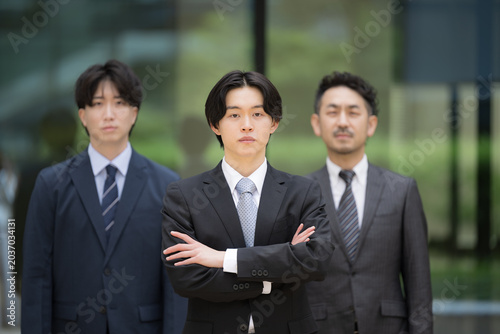 若手社員を中心に管理職とチームで成長する新卒の人材育成とキャリア形成のビジネスのリクルートイメージ　カメラ目線の腕を組む真剣な表情