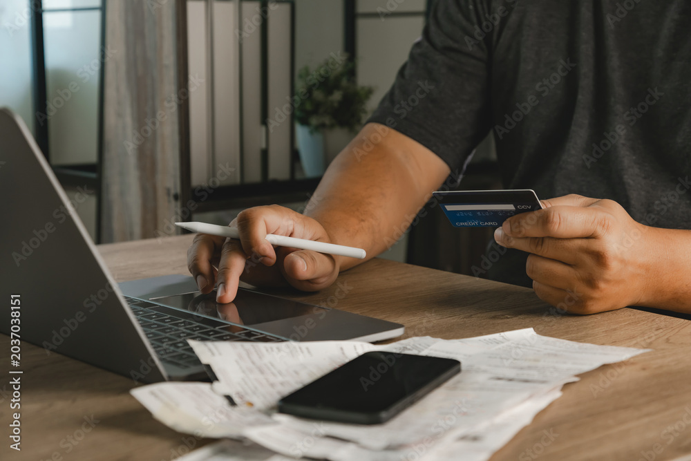 Fototapeta premium Person using laptop and holding credit card beside smartphone and shopping receipts for ecommerce sale, online payment, digital banking, discount promotion, and expense tracking workflow.