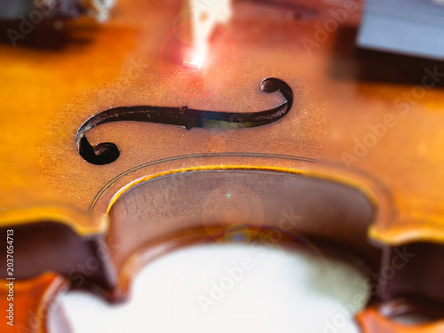 In selective focus of F-hole on violin body.show Part of acoustic instrument,blurry light around