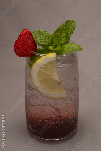Slika na platnu Layered strawberry lemonade with mint garnish, bright red puree settling at glas