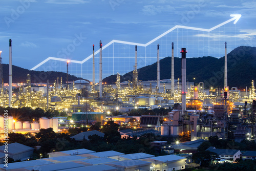 Industrial complex in Bang Lamung, Chonburi Province, Thailand in aerial view, illuminated refinery industrial infrastructure, overlaid with rising financial graph symbolizing industrial growth.