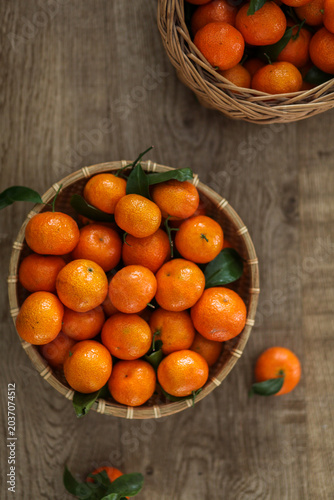 Fresh and juicy mandarins in woven baskets on wooden table