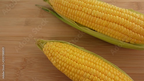 Fresh corn cob on wooden background top view.