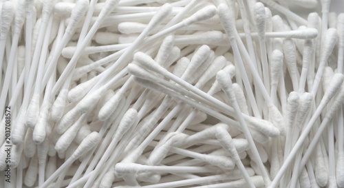 Abundant pile of white cotton swabs arranged in a random pattern creating a clean minimalist background texture for healthcare and personal hygiene concepts