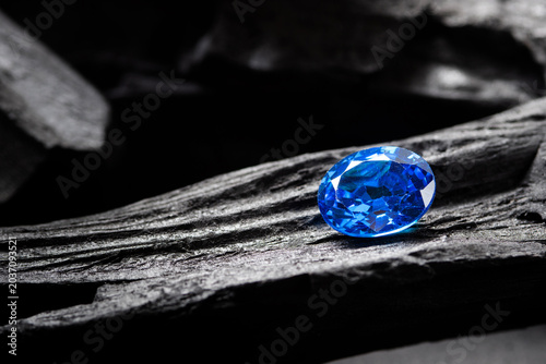 blue sapphire on black coal background, close up shot