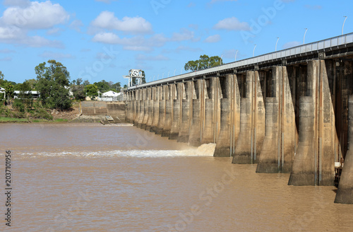 Fitzroy River Barrage releasing water into the muddy river under a blue sky in Rockhampton, Queensland, Australia