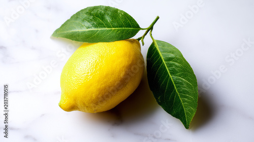 Fresh lemon with green leaves on a marble surface, showcasing vibrant yellow against a clean white background.