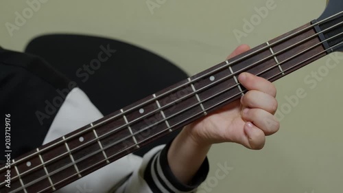 Close up of child hand fretting strings on dark acoustic guitar neck, learning to play music instrument against neutral background.