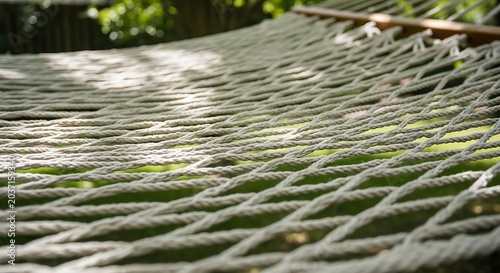 sturdy rope hammock showcasing its intricate weave against a blurred backdrop of lush green foliage.