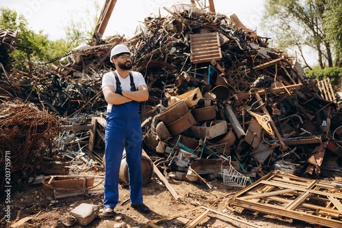 Фотография Worker standing with arms crossed at metal junkyard