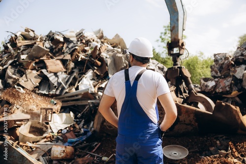 Принти на полотні Metal recycling worker looking at industrial scrap pile