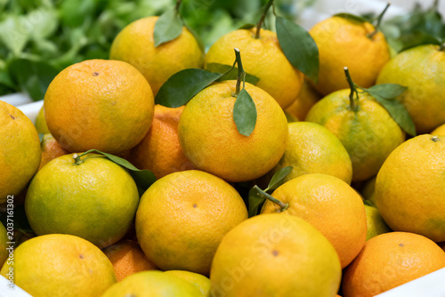Fresh ripe mandarins with green leaves in a market display