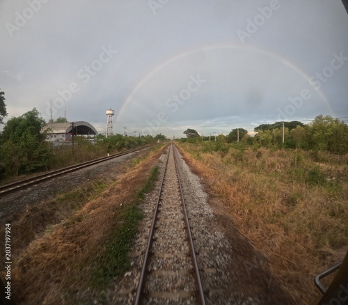 GoPro wide angle shot of train tracks fading into the horizon under a rainbow