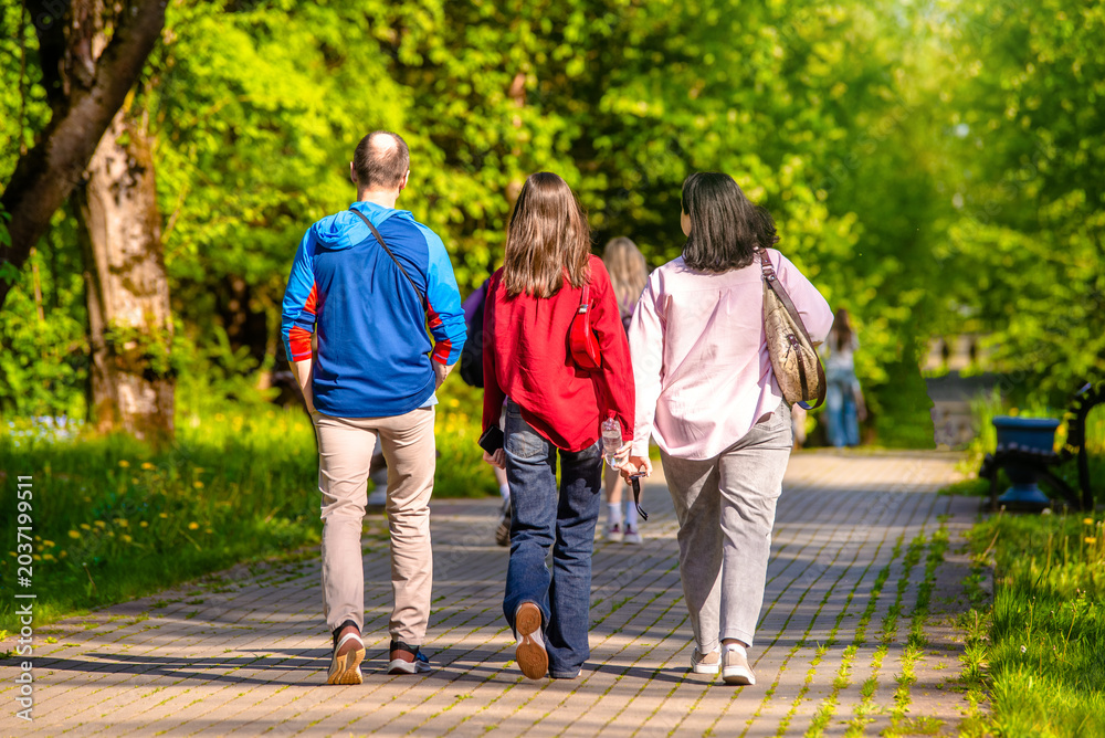 Fototapeta premium A man and two girls are walking in a city park 
