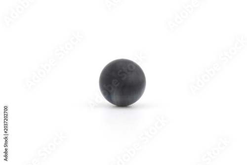 A blue tiger eye stone is positioned in the center of a white space. The light highlights its unique features, showing its round shape and smooth surface clearly.