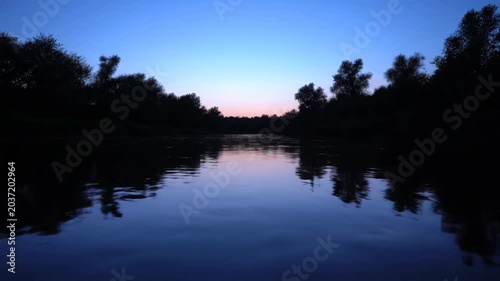 Serene River Scene at Dusk with Calm Waters and Silhouetted Trees.