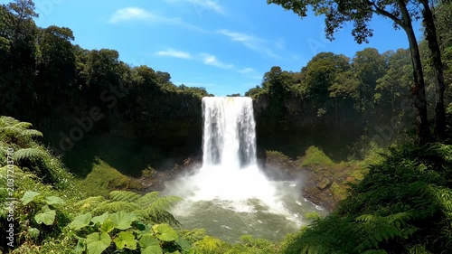 Majestic Waterfall Flowing Through Lush Green Forest Scene.