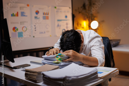 Overworked business professional resting head on documents at late night office