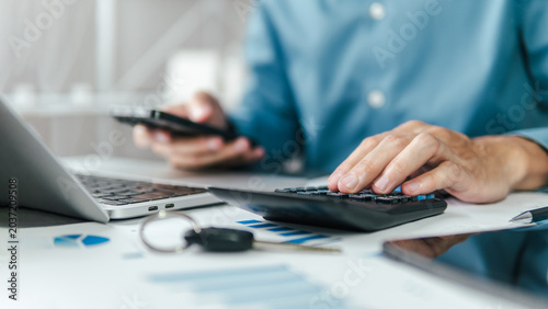 Obraz na plátne A male accountant calculating annual car tax, income and expense calculations, and analyzing trading reports; concepts of annual vehicle tax, and financial and tax systems