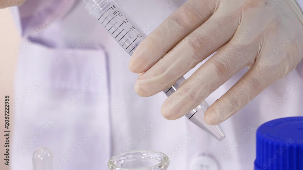 Fototapeta premium Scientist in Lab Coat Holding Plastic Graduated Tube Over Glassware